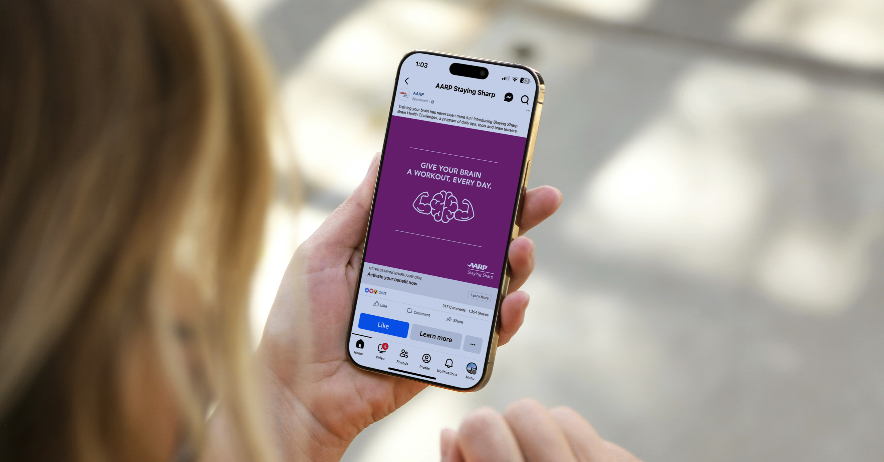 Woman holding a phone showing a mobile AARP Staying Sharp ad